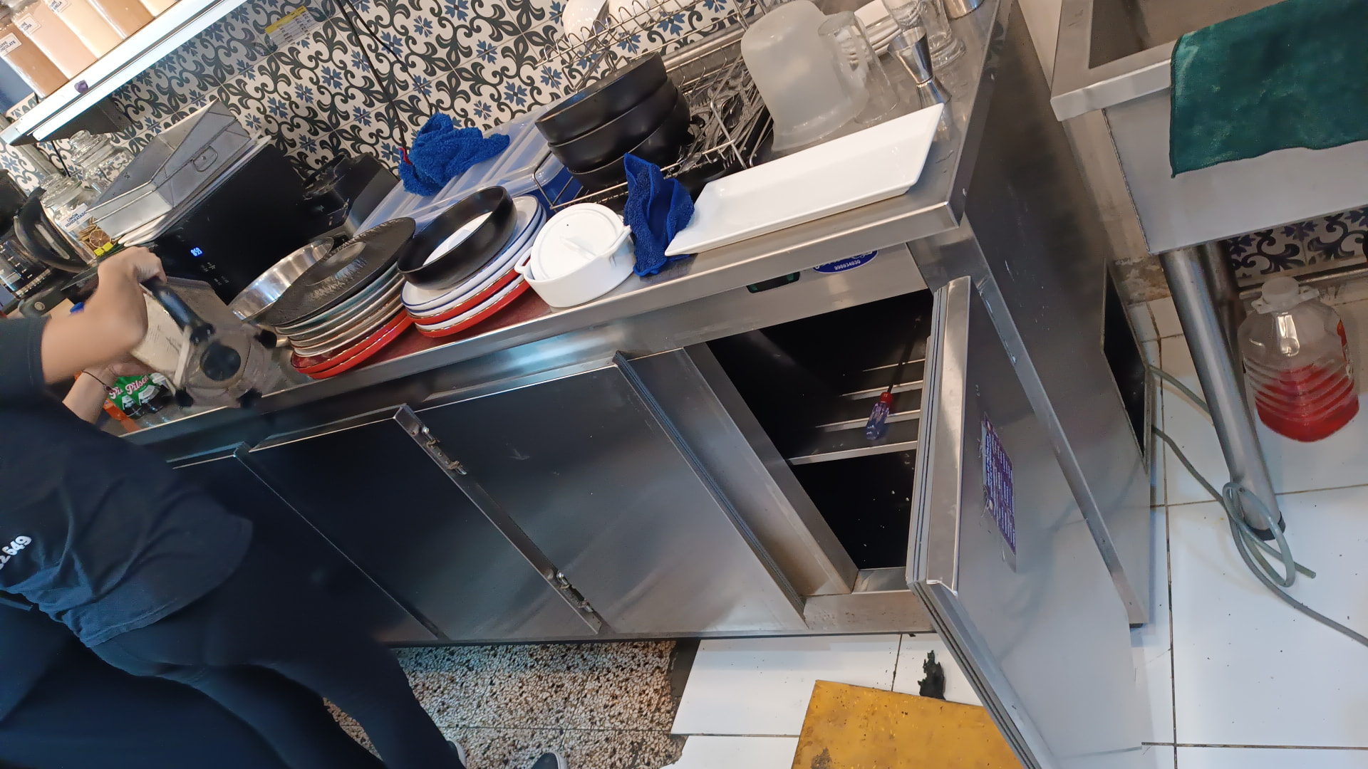 Técnico reparando mesa refrigerada bajo mostrador en cocina de restaurante en Lima